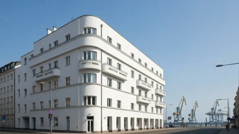 Biala modernistyczna kamienica w centrum Gdyni z portem w tle